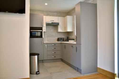 a kitchen with white cabinets and a stainless steel refrigerator at Red Watch Apartment in Oban