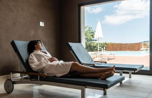 a woman sitting in a chair looking out a window at Grande Baia Resort & Spa in San Teodoro