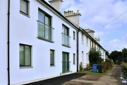 a row of white houses with windows on a street at Red Watch Apartment in Oban