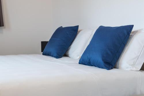 a white bed with blue pillows on it at Hotel Cascina Fossata & Residence in Turin