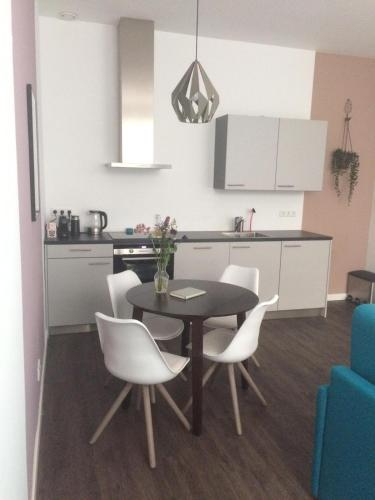 a kitchen with a dining table and white chairs at Slapen bij Van-V in Zierikzee