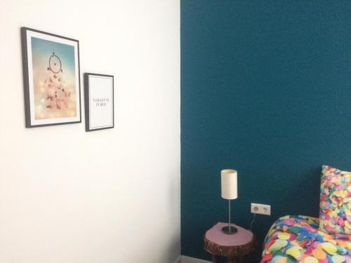a bedroom with a blue wall with a bed and a lamp at Slapen bij Van-V in Zierikzee