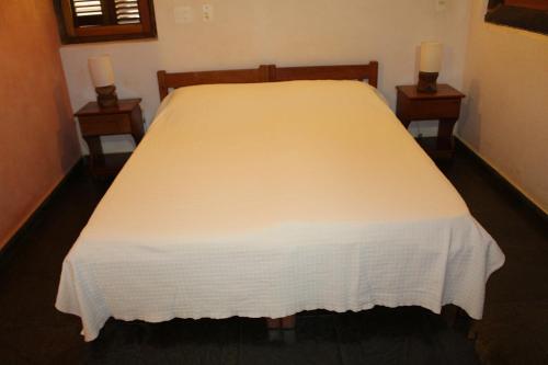 a bedroom with a white bed with two night stands at Pousada Canto Verde in Boicucanga