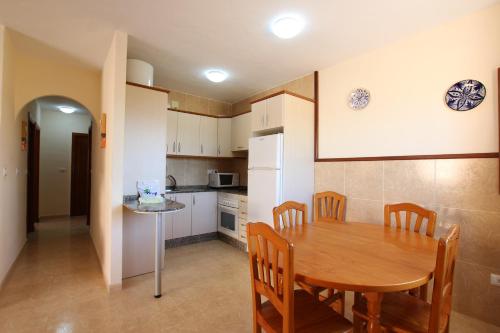 a kitchen and dining room with a wooden table and chairs at Apartamentos Tesy in La Manga del Mar Menor