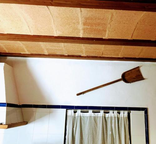 a clock on the wall above a window with a curtain at Ca na Brila in Campos