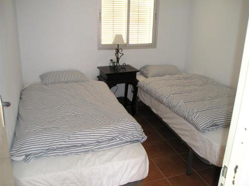 two beds in a room with a table and a window at Apartament Casa Levante in Vejer de la Frontera
