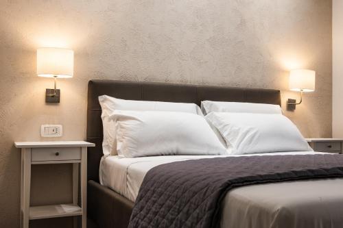 una camera da letto con un letto con cuscini bianchi e due luci di Prestige Rooms Chiaia a Napoli