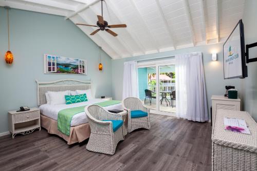 a bedroom with a bed and chairs and a patio at Pineapple Beach Club - All Inclusive - Adults Only in Willikies