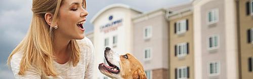 a woman holding a dog in front of a building at Candlewood Suites DFW West - Hurst by IHG in Hurst