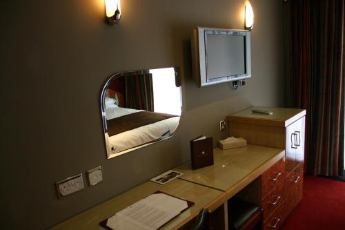 a room with a mirror and a desk with a television at Beamish Park Hotel in Beamish
