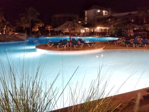 a swimming pool at night with chairs and tables at Ti-Colibris in Saint-François