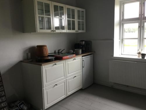 una cocina con armarios blancos y una ventana en Agerfeld gl. skole, en Holstebro