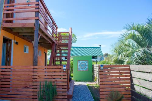 una valla de madera junto a una casa con una puerta verde en Aparts Dunas de Valizas en Barra de Valizas