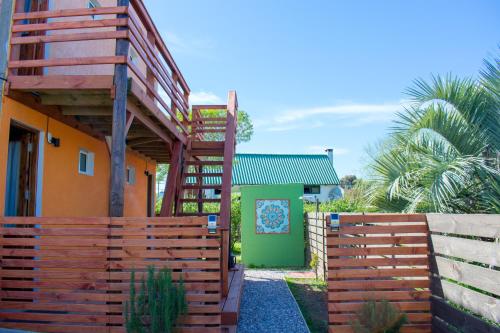 a wooden fence next to a house with a green door at Aparts Dunas de Valizas in Barra de Valizas