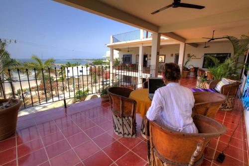 a person sitting at a table looking out at the ocean at Hotel La Quinta del Sol in Punta Mita