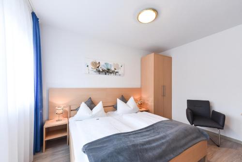 a bedroom with a white bed and a chair at Gasthof Kolb in Bayreuth