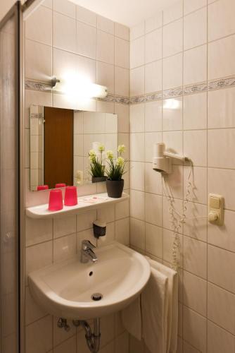 a white bathroom with a sink and a mirror at Gasthof Kolb in Bayreuth