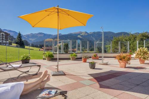 a person laying on a bench under a yellow umbrella at Apparthotel Talhof, Restaurant, Pool und Spa in Oberau