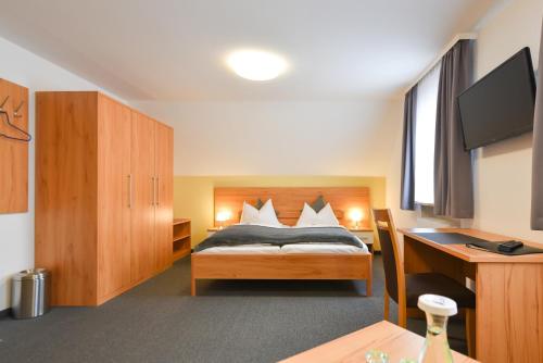 a bedroom with a bed and a desk and a television at Gasthof Kolb in Bayreuth