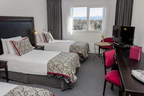 a hotel room with two beds and a television at Lagos Del Calafate in El Calafate