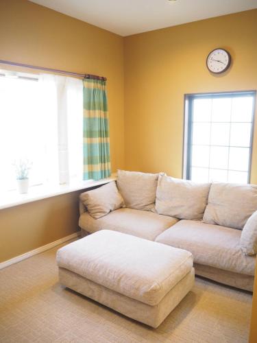 a living room with a couch and a clock on the wall at Guest House Bostons / Vacation STAY 5142 in Niigata