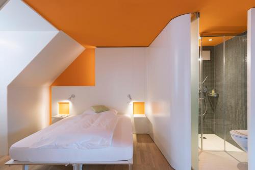 ザンクト・ガレンにあるホテル ドンのオレンジ色の天井のベッドルーム1室、ベッド1台、シャワーが備わります。