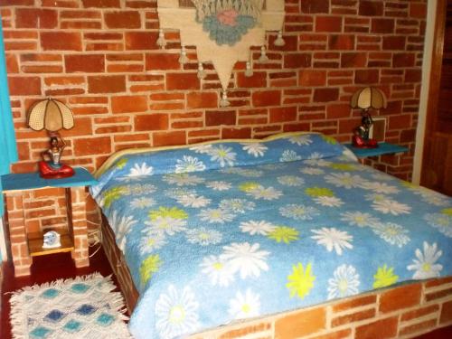 a bed in a brick room with two lamps on tables at Hotel Casa de la Luna in San Juan Teotihuacán