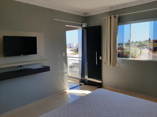 a living room with a television and a large window at Pousada Viva Maragogi in Maragogi