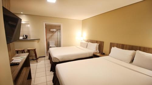 a hotel room with two beds and a flat screen tv at Holiday Inn Fortaleza by IHG in Fortaleza