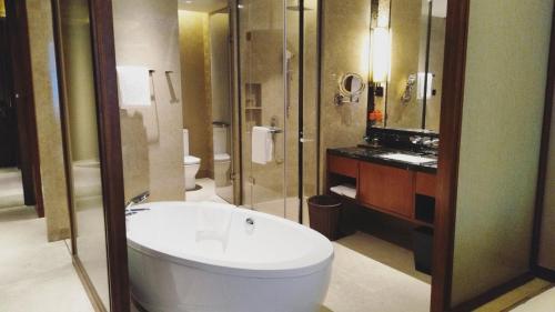 a bathroom with a white tub and a shower at Howard Johnson Neodalle Resort Zhangjiajie in Zhangjiajie