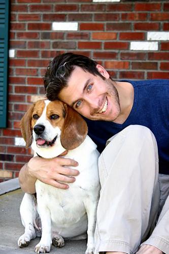 a man is hugging a brown and white dog at Keene Elm City Hotel, an Ascend Collection Hotel in Keene