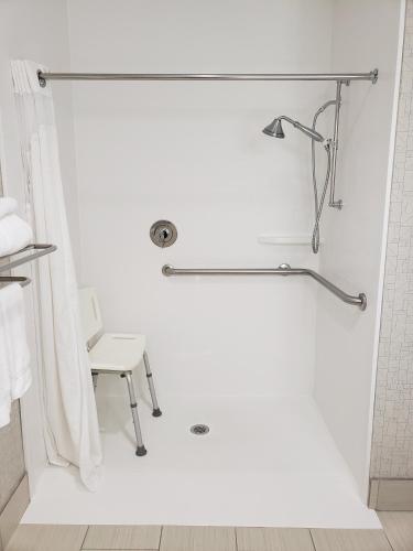 a white bathroom with a shower with a chair at Holiday Inn Express Edgewood-Aberdeen-Bel Air in Edgewood