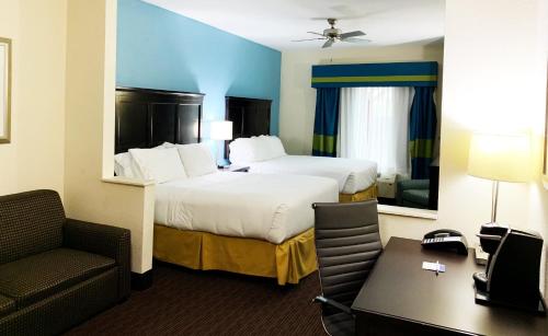 a hotel room with a bed and a chair and a desk at Holiday Inn Express Hotel & Suites Gainesville by IHG in Gainesville