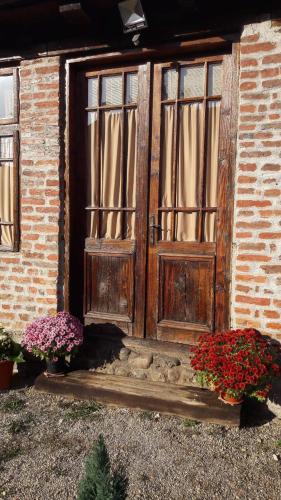 a wooden door with two windows and some flowers at Old Court in Curtea de Argeş