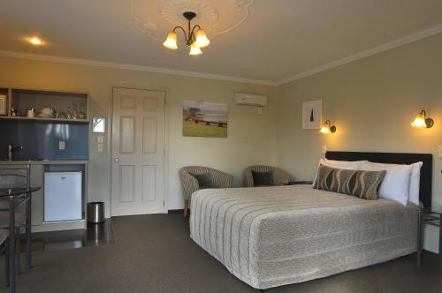 a bedroom with a bed and a table and a kitchen at Silver Fern Rotorua Suites & Spa in Rotorua