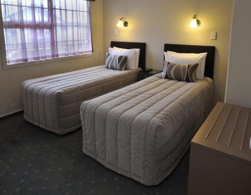 two beds in a hotel room with two bedsskirtspectspectssenalsenal at Silver Fern Rotorua Suites & Spa in Rotorua