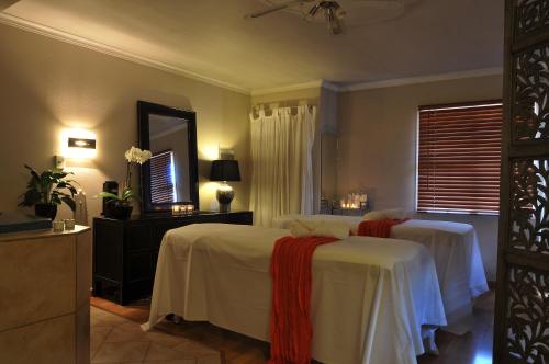 a bedroom with two beds with white sheets and a mirror at Silver Fern Rotorua Suites & Spa in Rotorua