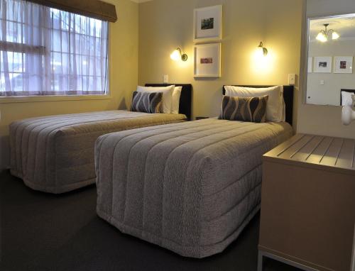 two beds in a hotel room with two bedsskirtspectspectspectssenalsenalsenal at Silver Fern Rotorua Suites & Spa in Rotorua