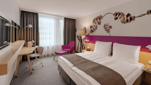 a hotel room with a large bed and a desk at Holiday Inn Frankfurt - Alte Oper by IHG in Frankfurt/Main