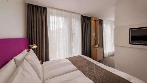 a hotel room with a bed and a flat screen tv at Holiday Inn Frankfurt - Alte Oper by IHG in Frankfurt/Main