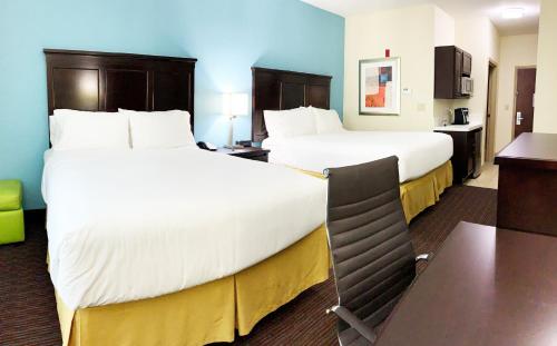 a hotel room with two beds and a desk at Holiday Inn Express Hotel & Suites Gainesville by IHG in Gainesville