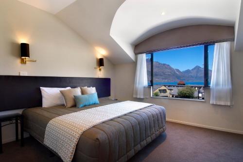 a bedroom with a large bed and a large window at Hurley's of Queenstown in Queenstown
