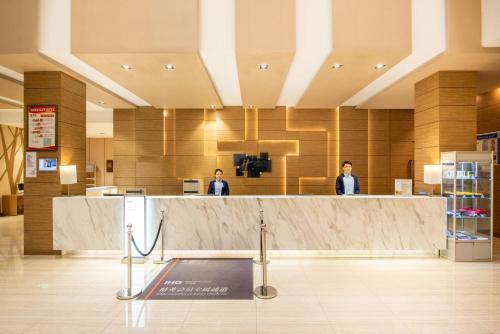 two people standing at a counter in a lobby at Holiday Inn Express Ordos Dongsheng by IHG in Ordos