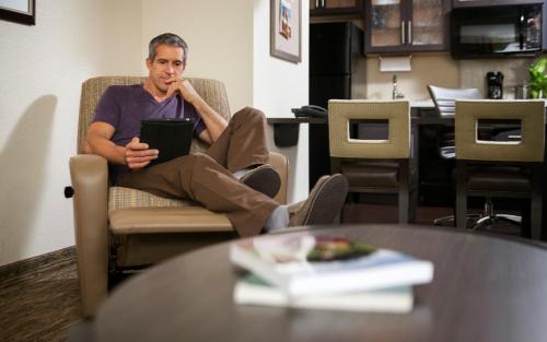 a man sitting in a chair with a tablet at Candlewood Suites - Frisco by IHG in Frisco