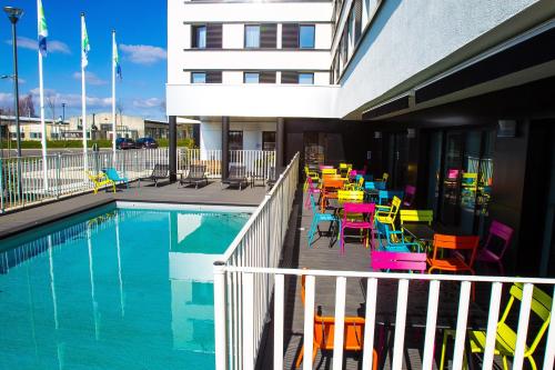 - une piscine avec des chaises et des tables colorées à côté d'un bâtiment dans l'établissement Holiday Inn Express Dijon by IHG, à Saint-Apollinaire