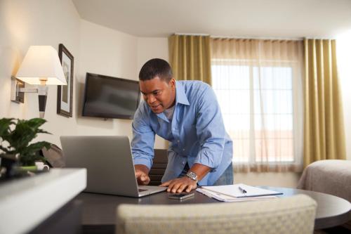 a man standing at a table with a laptop computer at Candlewood Suites - Frisco by IHG in Frisco