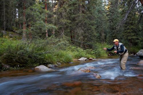 a man standing in a stream holding a fish at Holiday Inn Express Hotel & Suites Fraser Winter Park Area by IHG in Fraser