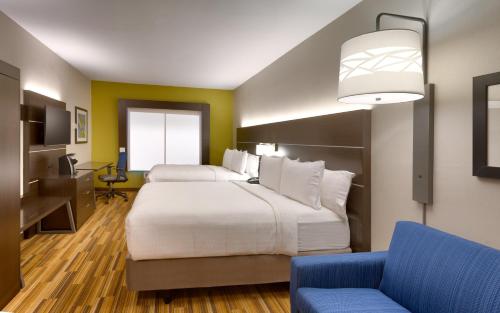 a hotel room with a large bed and a blue chair at Holiday Inn Express El Paso I-10 East by IHG in El Paso