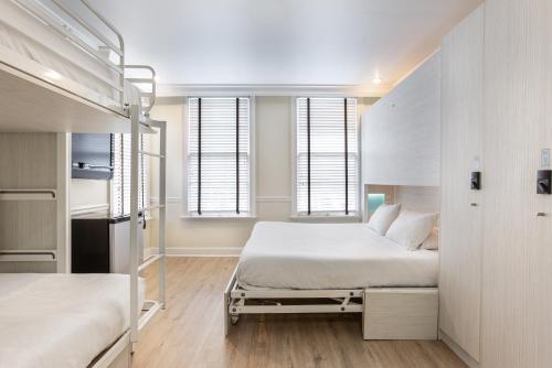 a white bedroom with a bed and two windows at Nyah - Adult Exclusive in Key West
