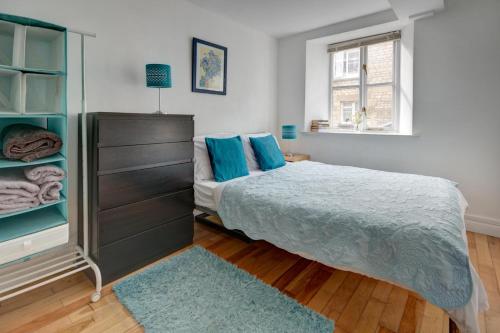 賽倫塞斯特的住宿－The Shop By Treetop Property，一间卧室配有一张床和一个带蓝色枕头的梳妆台。